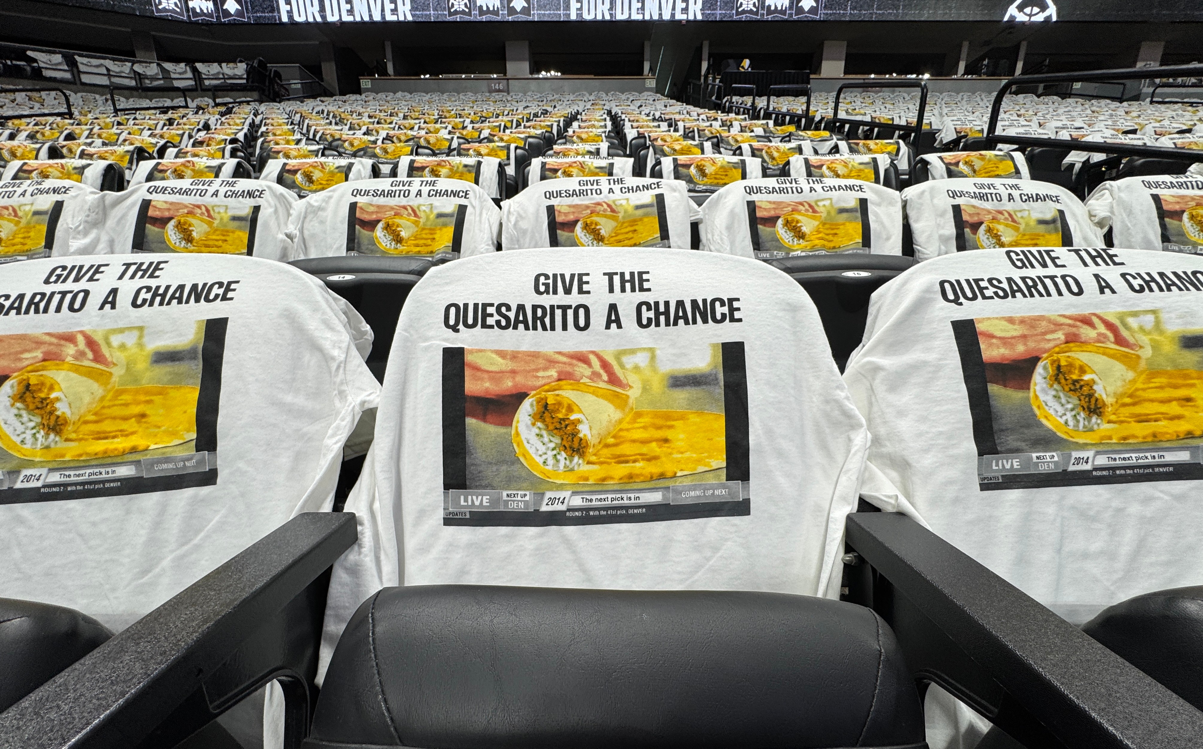 Image of the stadium seats with shirts draped over them saying "Give the Quesarito a chance" 